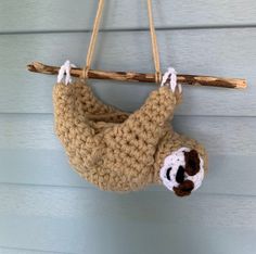 a crocheted slotty hanging from a wooden branch on the wall with white strings