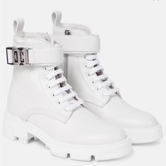 a pair of white boots with buckles on the front and side, sitting on a white surface