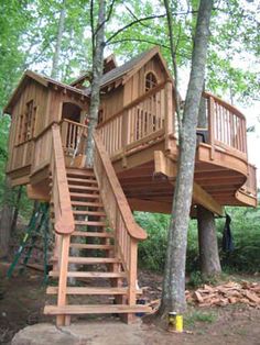 a tree house built in the woods with stairs leading up to it's roof