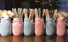 four mason jars with straws and flowers in them