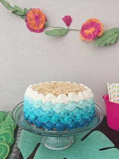 a cake with blue, white and pink frosting sitting on top of a table