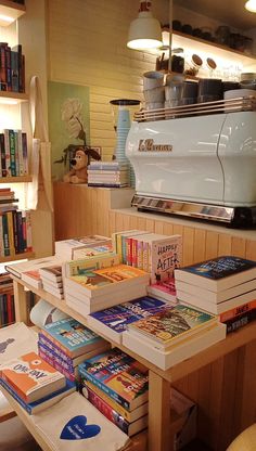 there are many books on the table in this room and one has a coffee maker