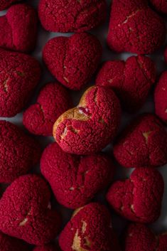 several red heart shaped cookies are arranged on a white surface