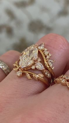 a close up of a person's hand with two rings on their fingers and one ring in the shape of a leaf