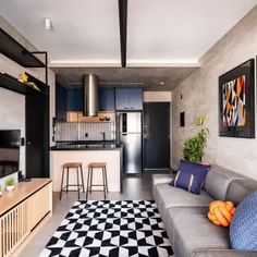 a living room filled with furniture and a flat screen tv mounted to a wall next to a kitchen