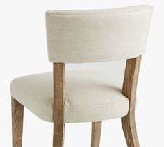 an upholstered chair with wooden legs and a white fabric seat cover on the back