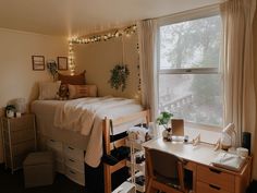 a bedroom with a bed, desk and chair next to a window covered in christmas lights