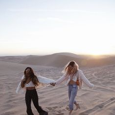 two girls walking in the sand holding hands