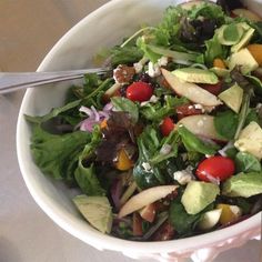 a white bowl filled with salad on top of a table next to utensils