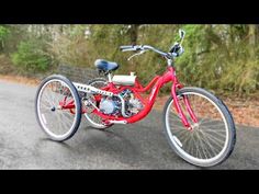 a red bike parked on the side of a road next to some bushes and trees