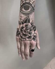 a hand with an all seeing tattoo on it and a rose in front of the eye