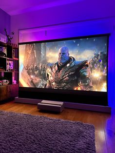 a large screen television sitting on top of a wooden floor next to a purple rug