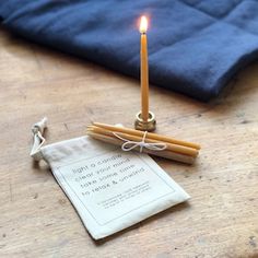 a lit candle sitting on top of a wooden table next to an envelope with writing