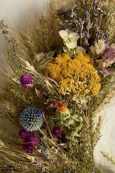 a bunch of flowers that are sitting on a table together in front of a white wall