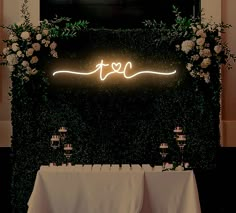 the table is set up with white linens and greenery, along with candles