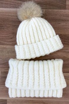 two white knitted hats with pom - poms