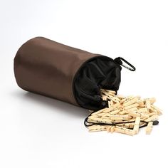 a brown bag filled with wooden sticks on top of a white table next to a pile of clothes pins