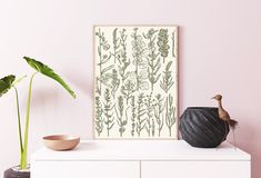 a white dresser topped with vases and plants next to a painting on the wall