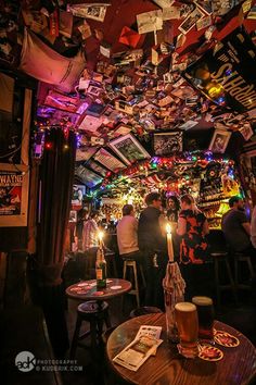 people sitting at tables in a bar with many pictures hanging from the ceiling