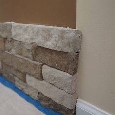 a brick wall with blue tape on the bottom and tan walls in the back ground