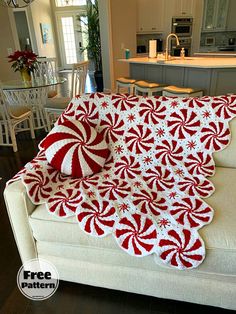 a red and white crocheted christmas afghan on a couch in a living room