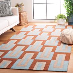 a living room area with a rug, couch and potted plant