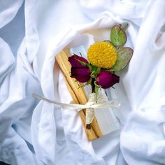 flowers are placed on top of a white cloth and tied in a knot with two wooden sticks