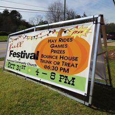 a sign advertising an event in front of a road with trees and grass on both sides