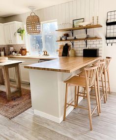 a kitchen with white cabinets and wooden stools in front of the island countertop