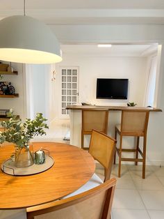 a dining room table with chairs and a television on the wall