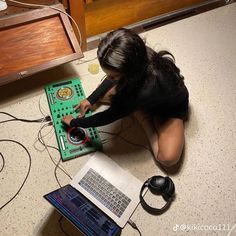 a woman sitting on the floor working on an electronic device