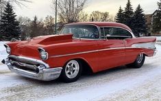 an old red car is parked in the snow