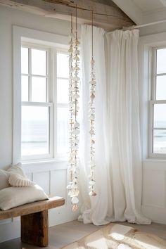 a room with white curtains and wooden bench