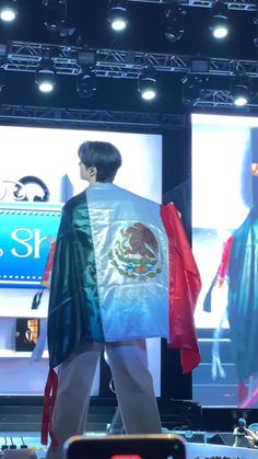 a man is walking down the runway with a mexican flag on his shirt and pants