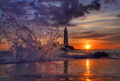 water splashing on the beach with a lighthouse in the background at sunset or dawn