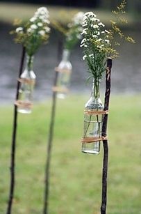 four vases with flowers in them are hanging from the poles on the grass field