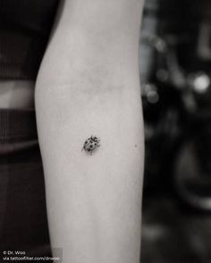 a black and white photo of a woman's arm with a small tattoo on it