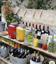 a wooden bench filled with lots of bottles and buckets full of drinks on top of it