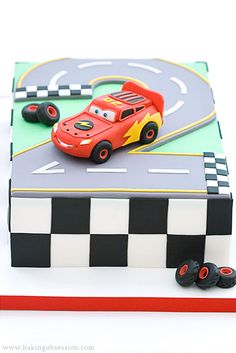 a birthday cake made to look like a race track with cars on the road and checkered blocks