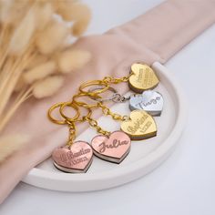 four heart shaped key chains sitting on top of a white plate next to dried flowers