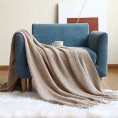 a blue couch with a blanket on it and a white rug in front of it