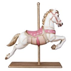 a white horse with pink and gold harnesses on it's back, standing on a wooden pole