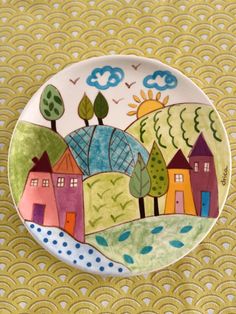 a plate with houses painted on it sitting on top of a tablecloth covered surface