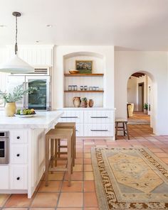 a large kitchen with white cabinets and counter tops, along with an area rug on the floor