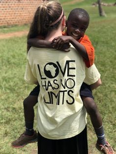 two children hugging each other outside in the grass, one is wearing a t - shirt that says love has no limits