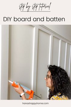 a woman is working on the wall with an orange and white paint roller in front of her