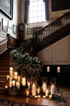 candles and greenery are arranged on the floor in front of an ornate stair case