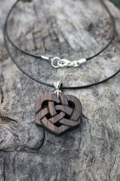 a wooden heart shaped pendant on a leather cord