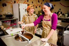 two women in aprons are preparing food together