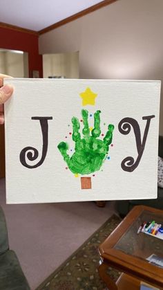 a person holding up a card with the word joy painted on it